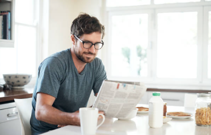 homeowner sitting at a kitchen table reading a printed warranty document